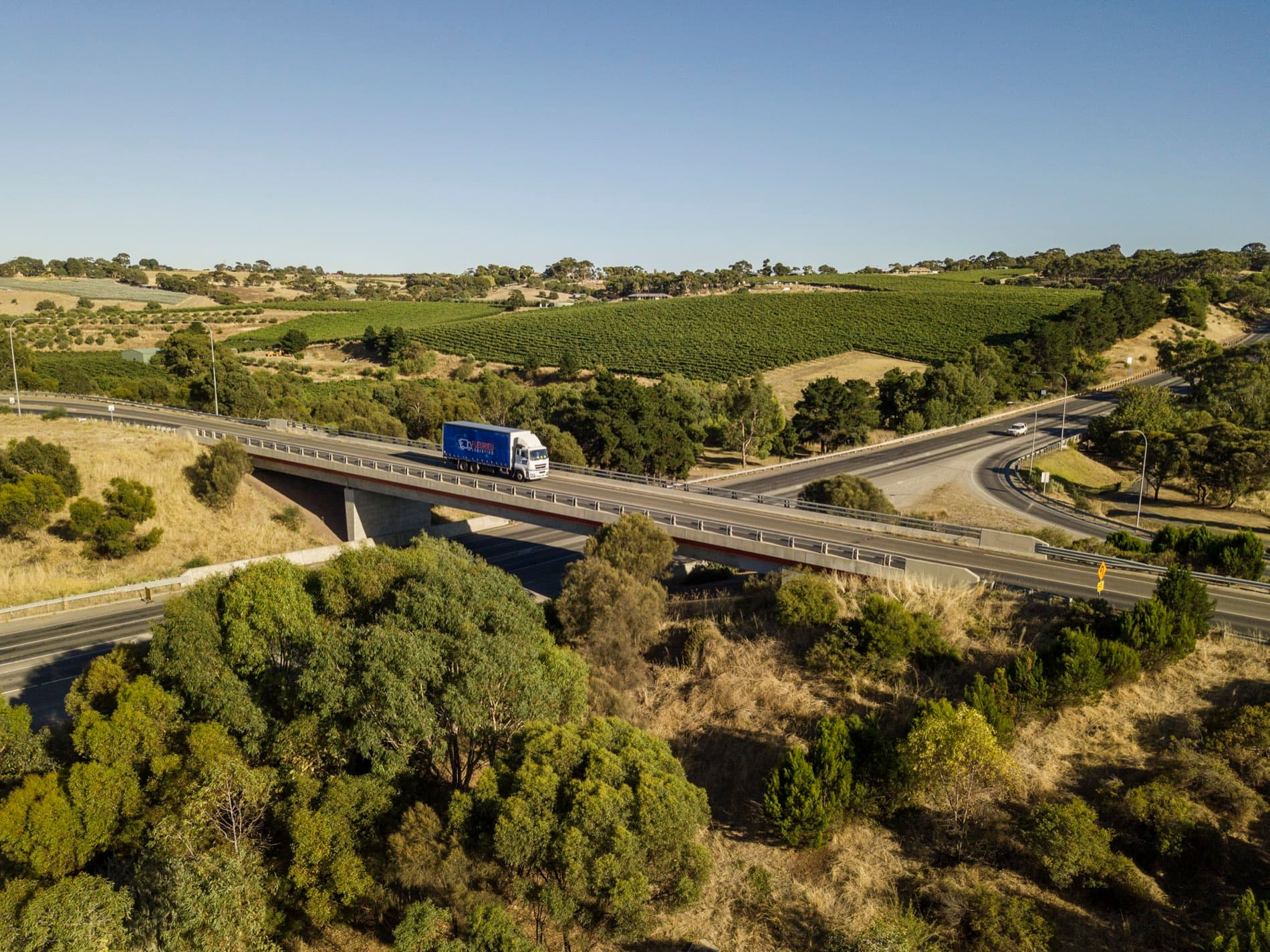 A Fleurieu Logistics truck crossing a bridge through the McLaren Vale vineyards